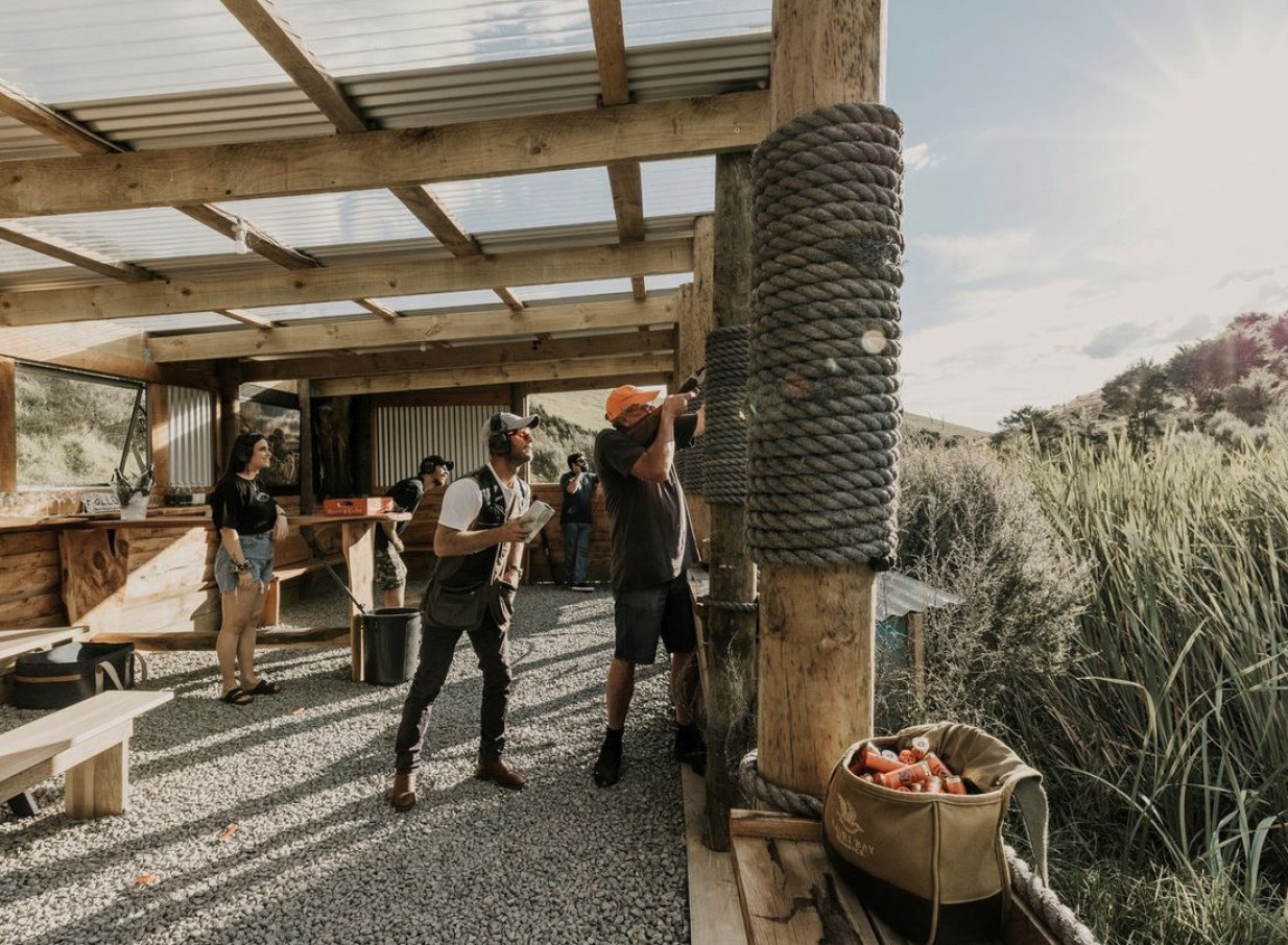 Guests enjoy clay target shooting at Kauri Bay's rustic outdoor range in Auckland.