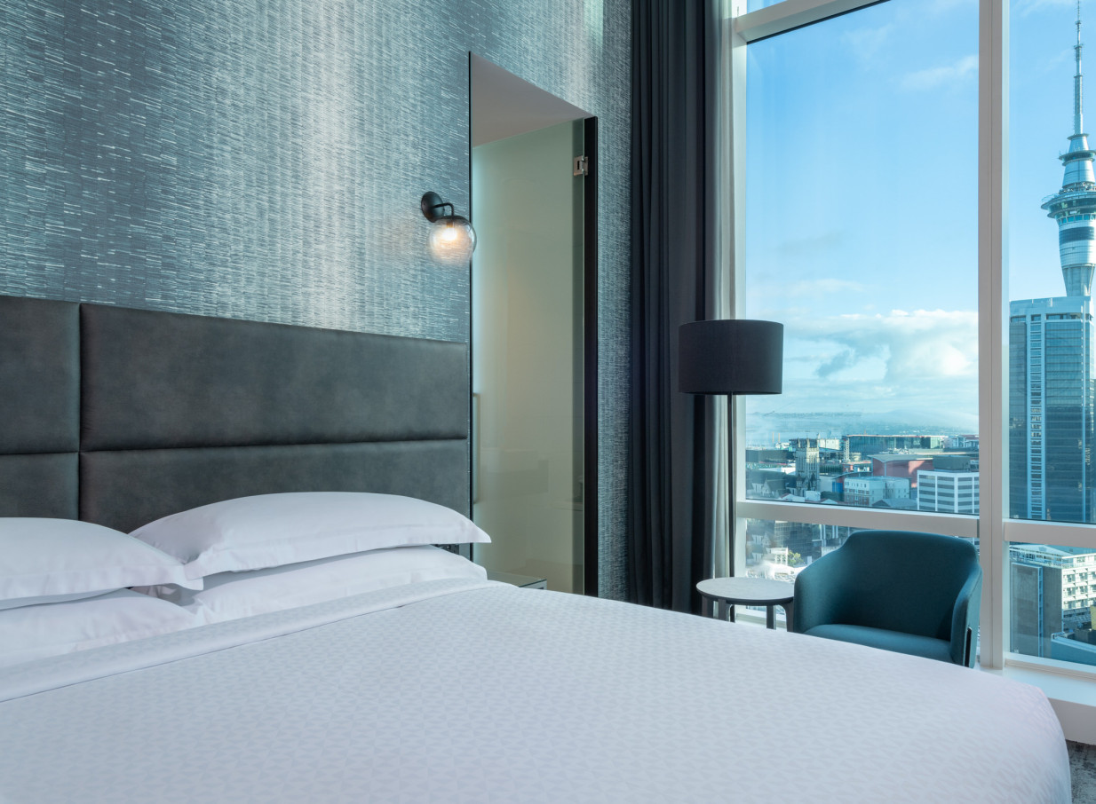 A contemporary hotel bedroom at Four Points by Sheraton Auckland, offering city views of Auckland's Sky Tower.