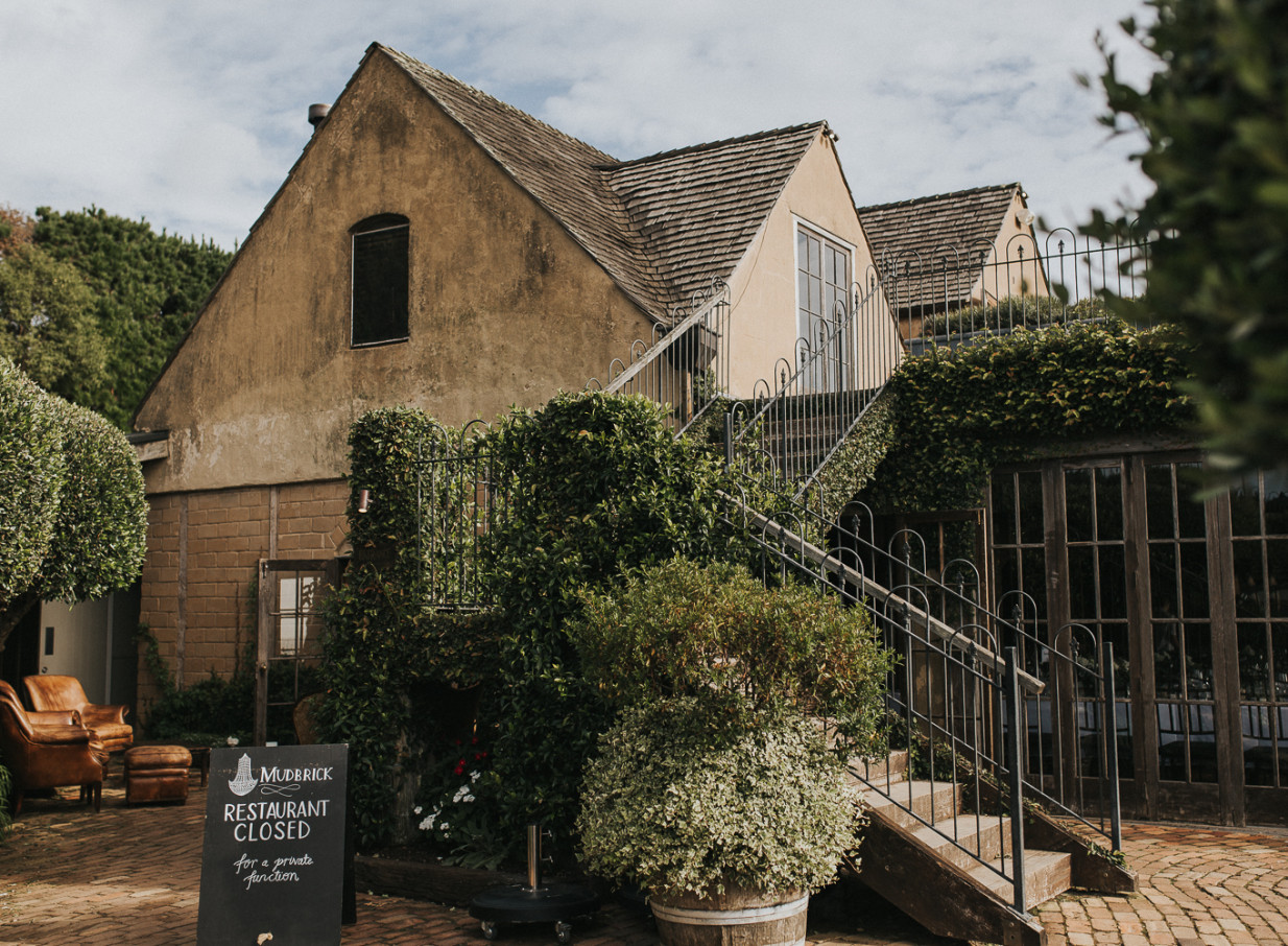 Tuscan-inspired mud-brick architecture at Mudbrick, Waiheke Island, with lush gardens and stone steps.