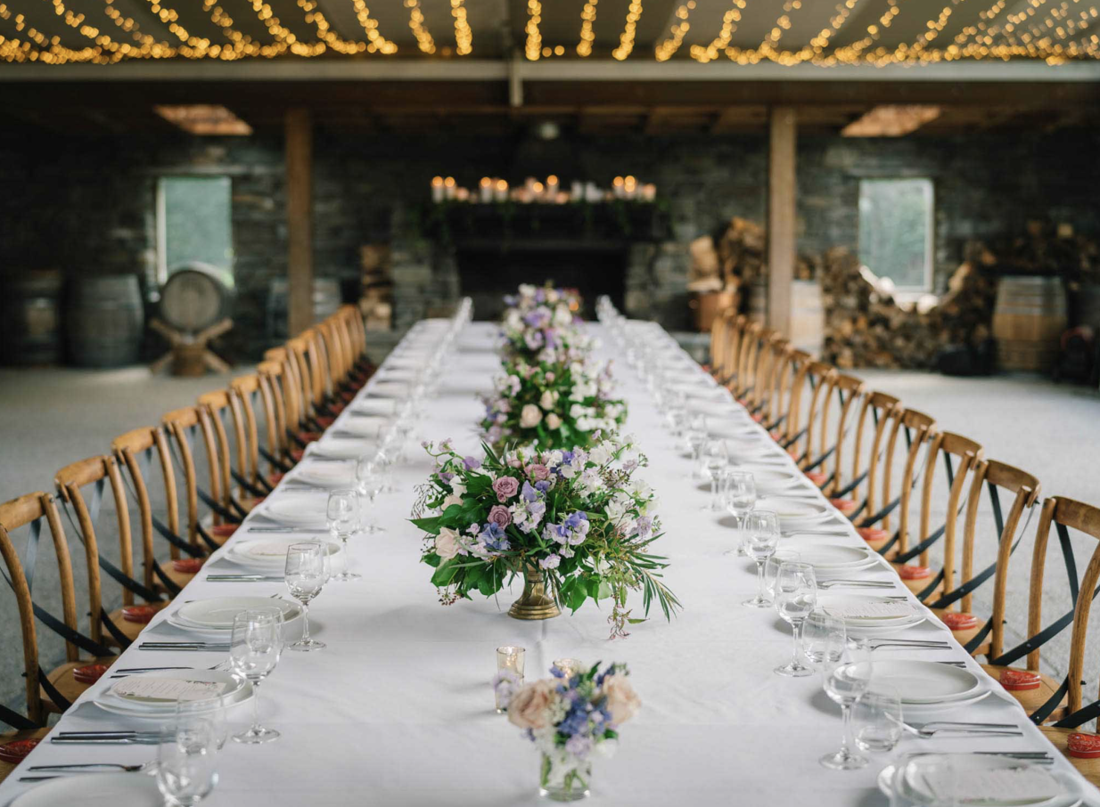 A long table dining event in the rustic stone interior of Winehouse, Queenstown, featuring string lights.