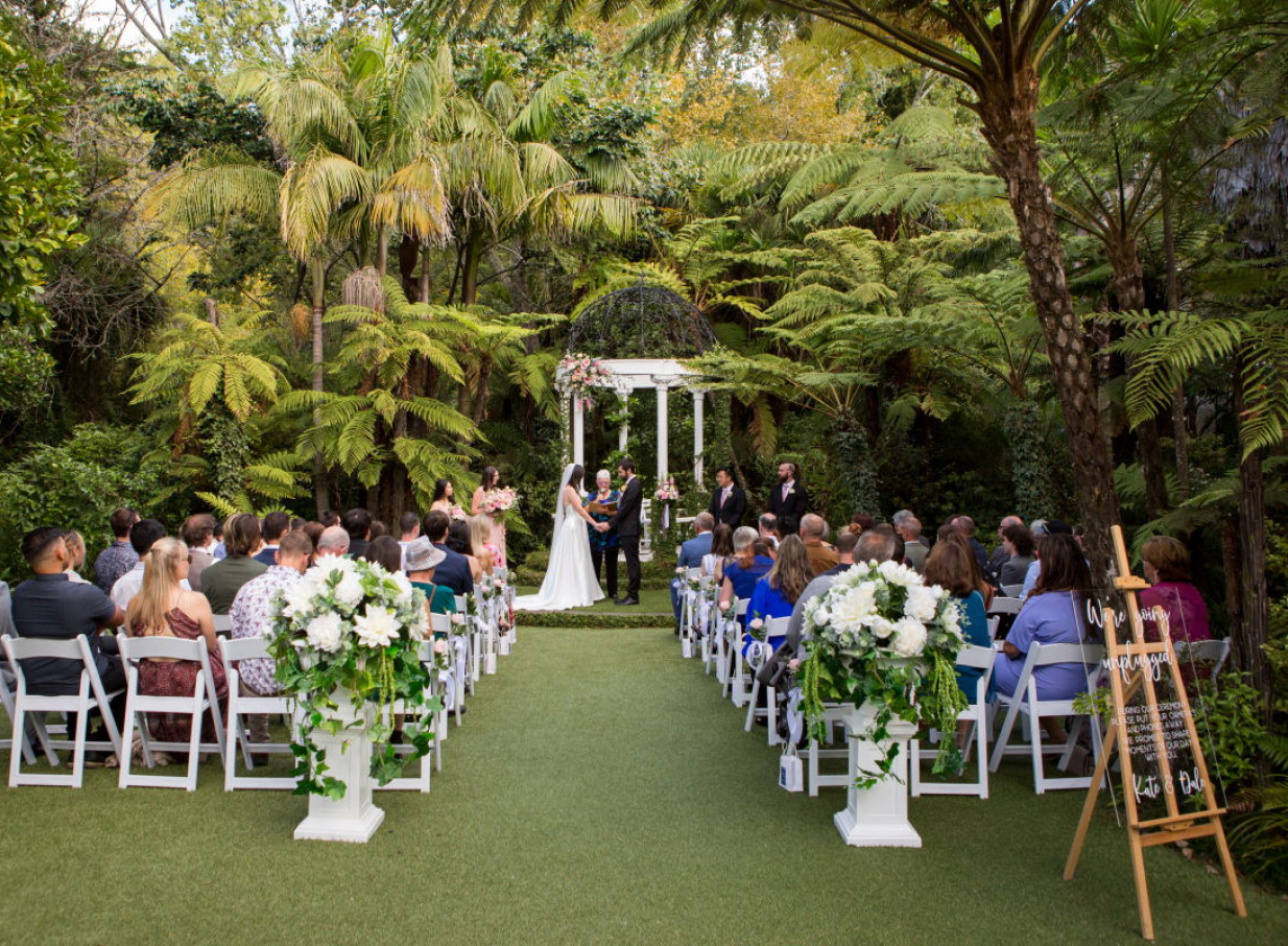 An outdoor wedding ceremony at Tui Hills, Auckland, features an iconic rotunda nestled within a lush native garden setting.