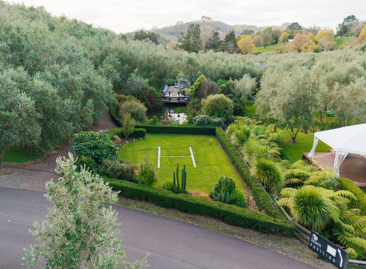A Mediterranean-inspired outdoor event lawn and helipad at Bracu Estate, Auckland, nestled amidst olive groves.