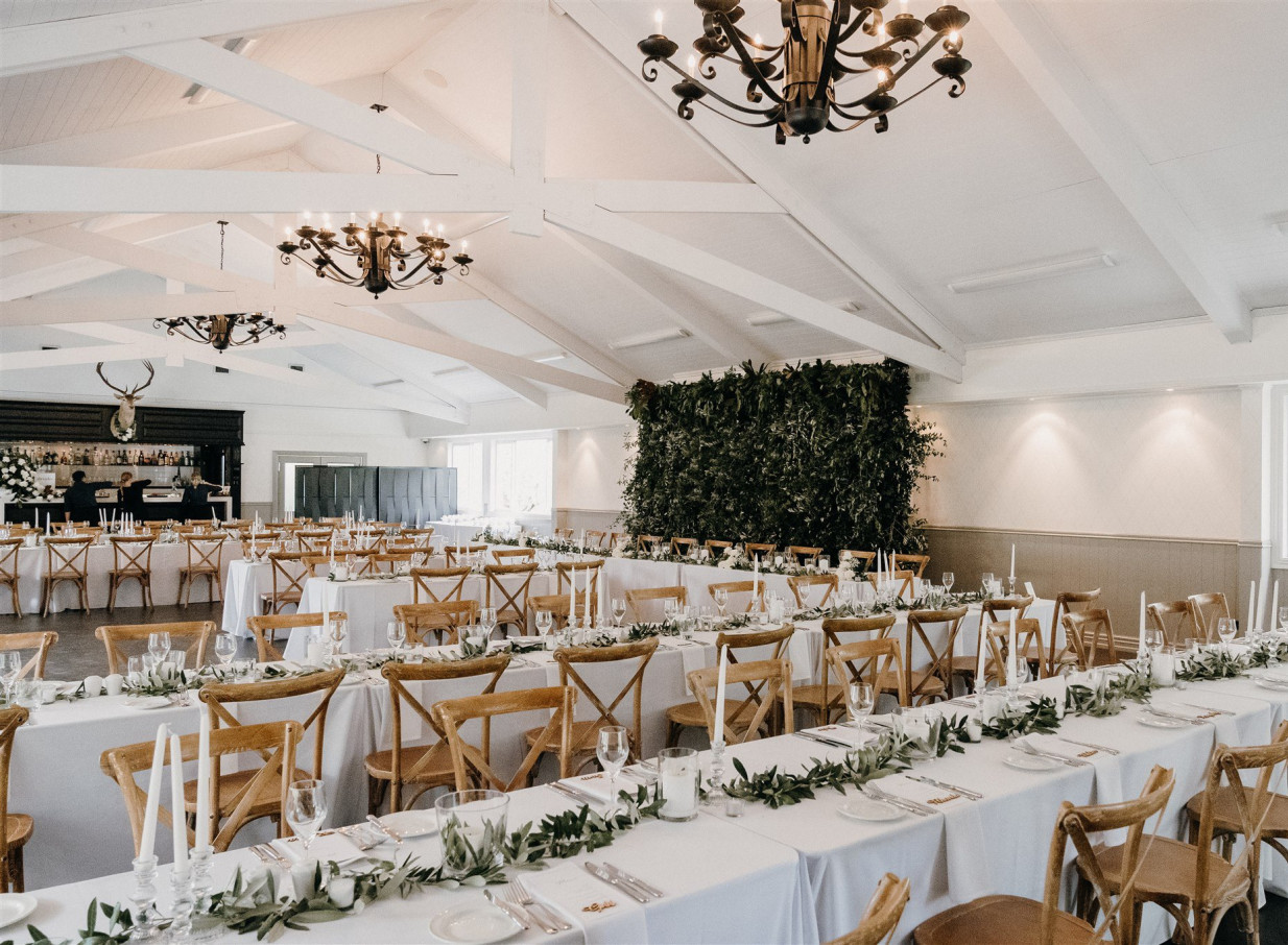 An elegant, Mediterranean-inspired reception hall at Bracu Estate in Auckland, set for a wedding with long tables and cross-back chairs.