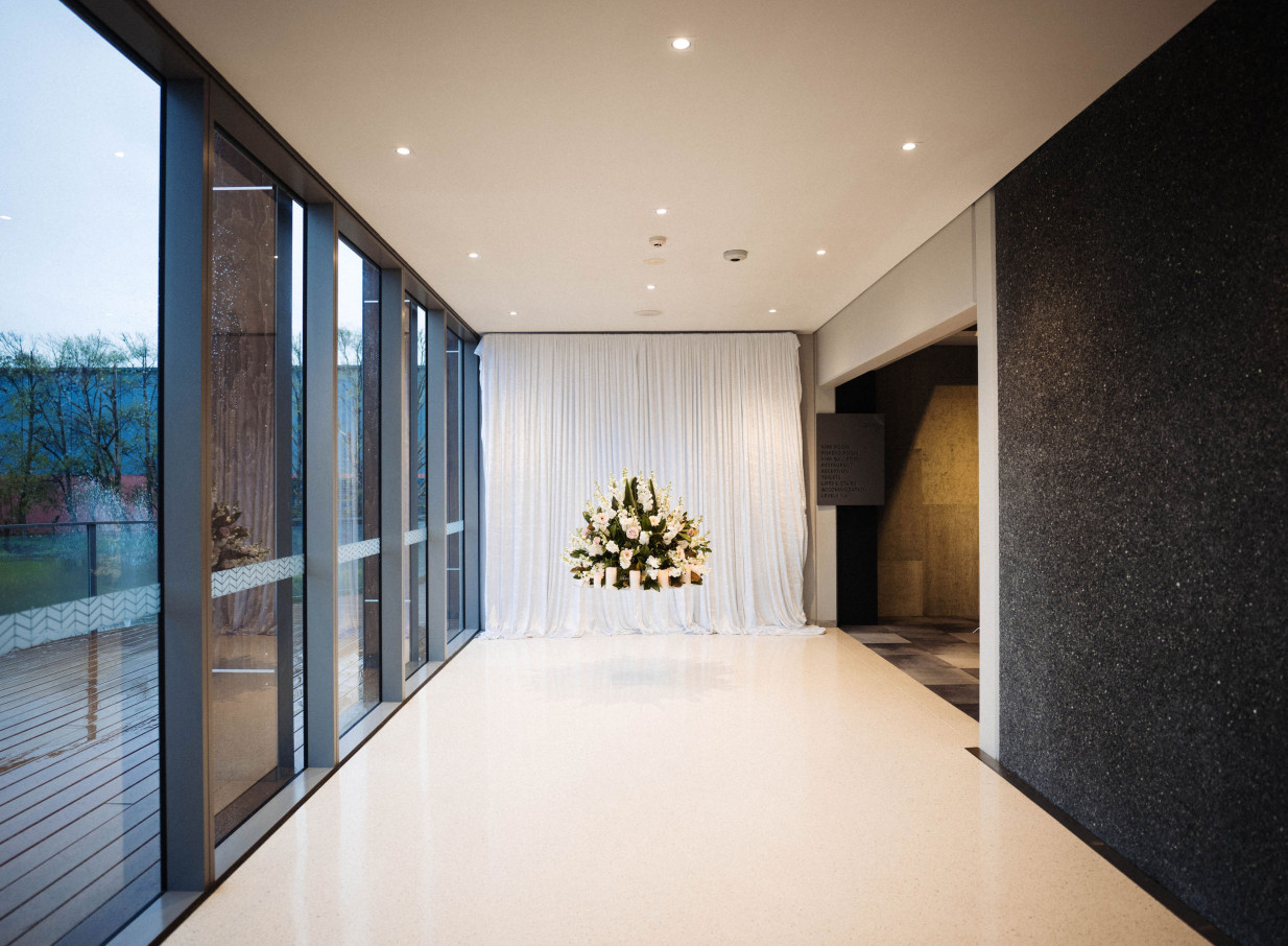 A modern event space at JetPark Auckland Hotel, featuring large windows and a prominent white floral arrangement.