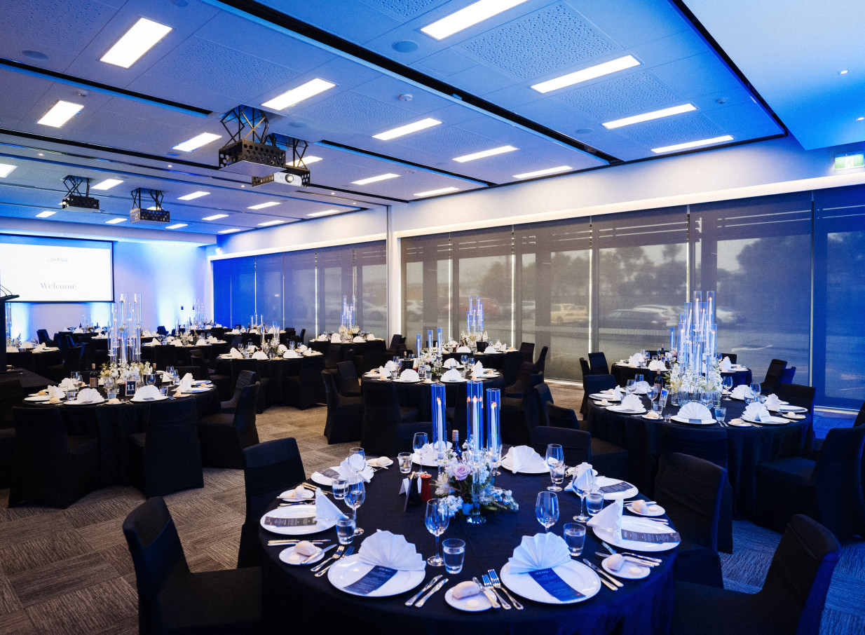 JetPark Auckland Hotel's modern event space features elegant banquet tables under atmospheric blue lighting.