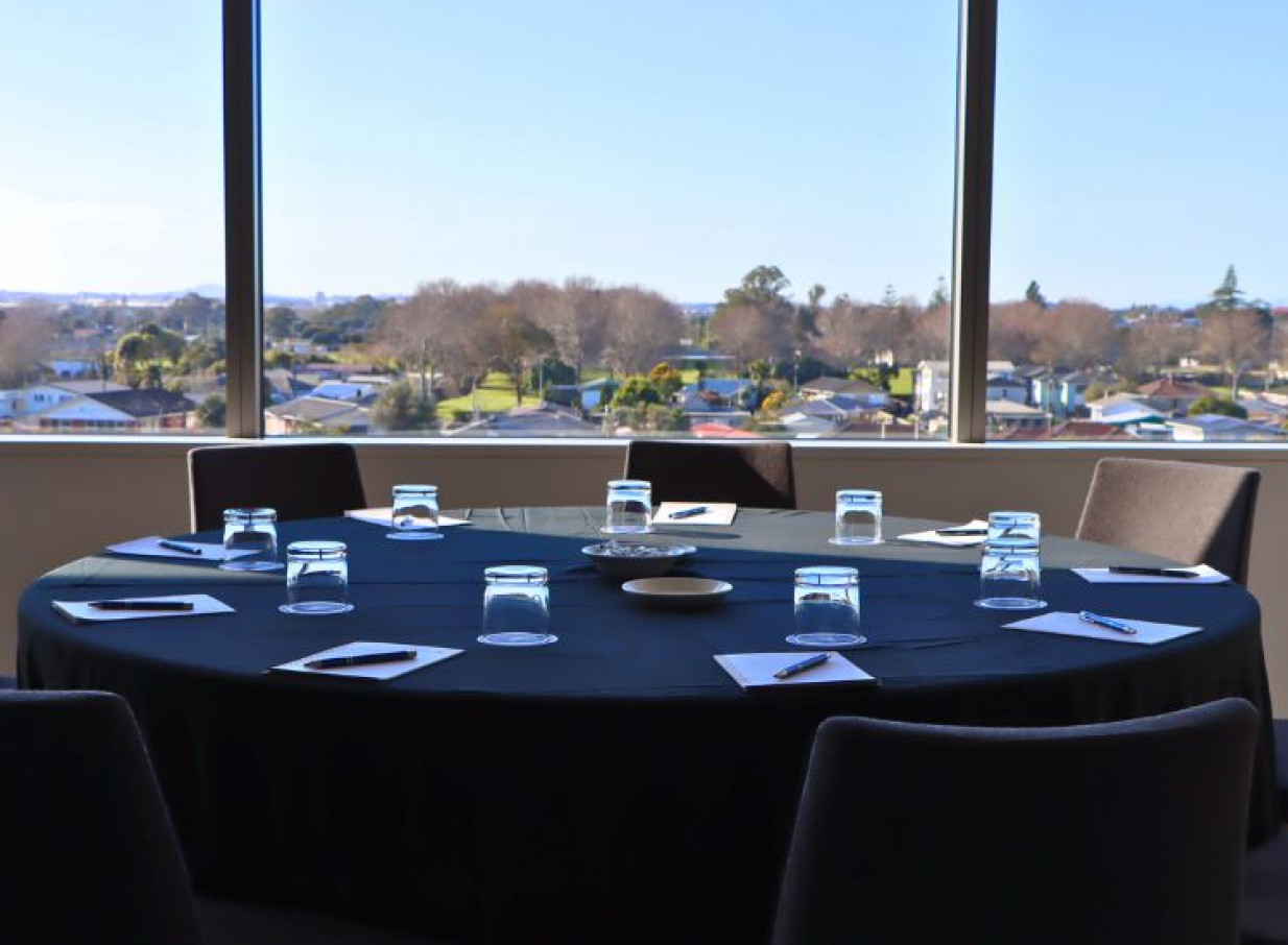 A modern meeting room at JetPark Auckland Hotel, featuring a round table and a panoramic view of Auckland.