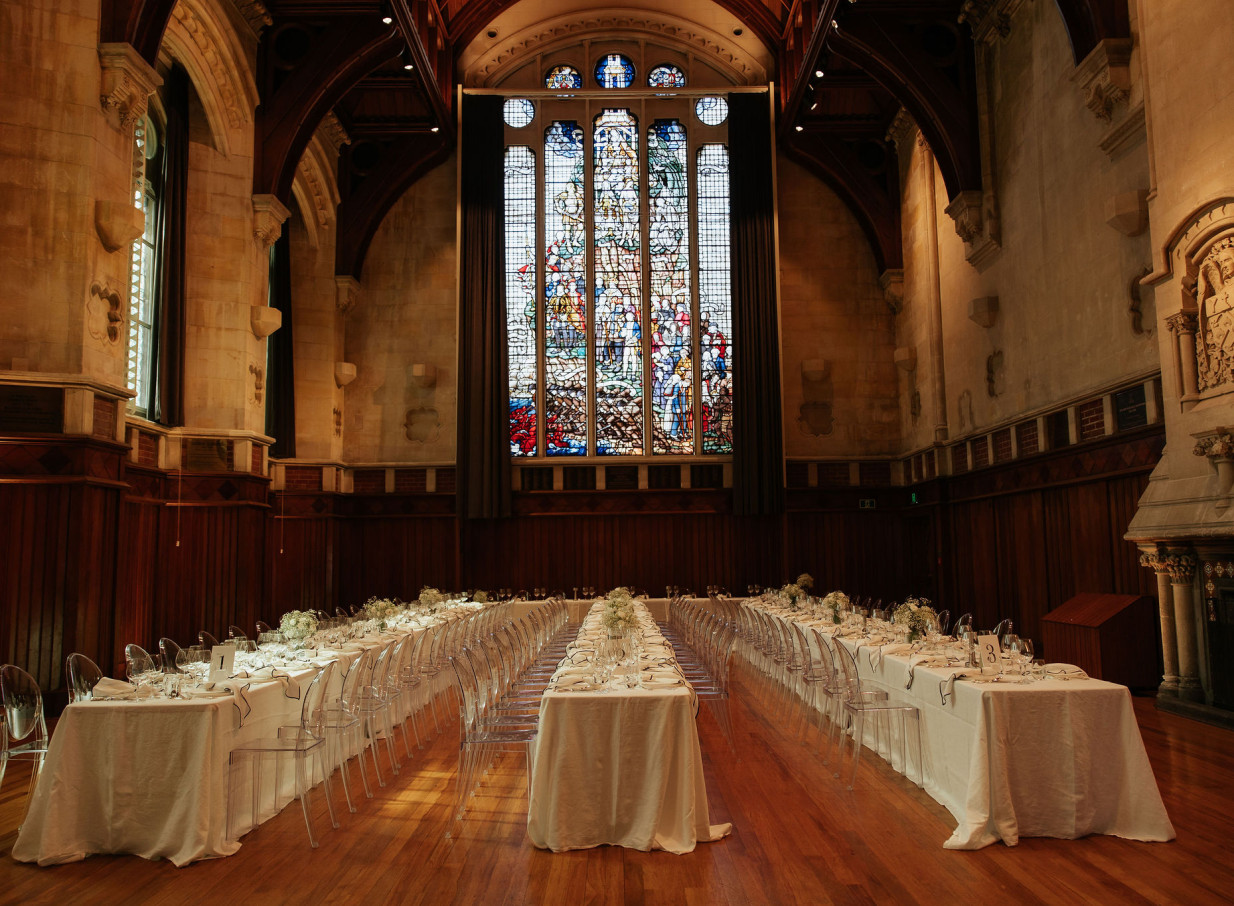 Formal dining event in the Gothic Revival Great Hall, Christchurch, with its impressive stained-glass window.