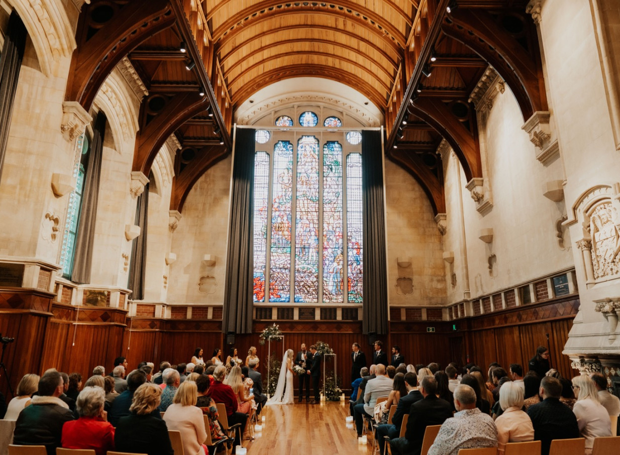 A wedding ceremony within the Gothic Revival Great Hall, Christchurch, showcasing its vaulted ceiling and stained glass.