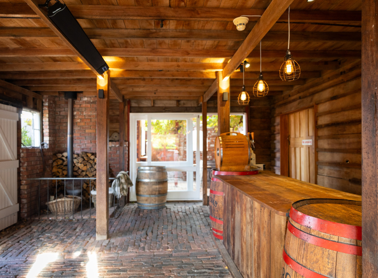 A rustic-charmed barn bar area at Larcomb Vineyard in Christchurch, featuring exposed wooden beams and a timber bar.