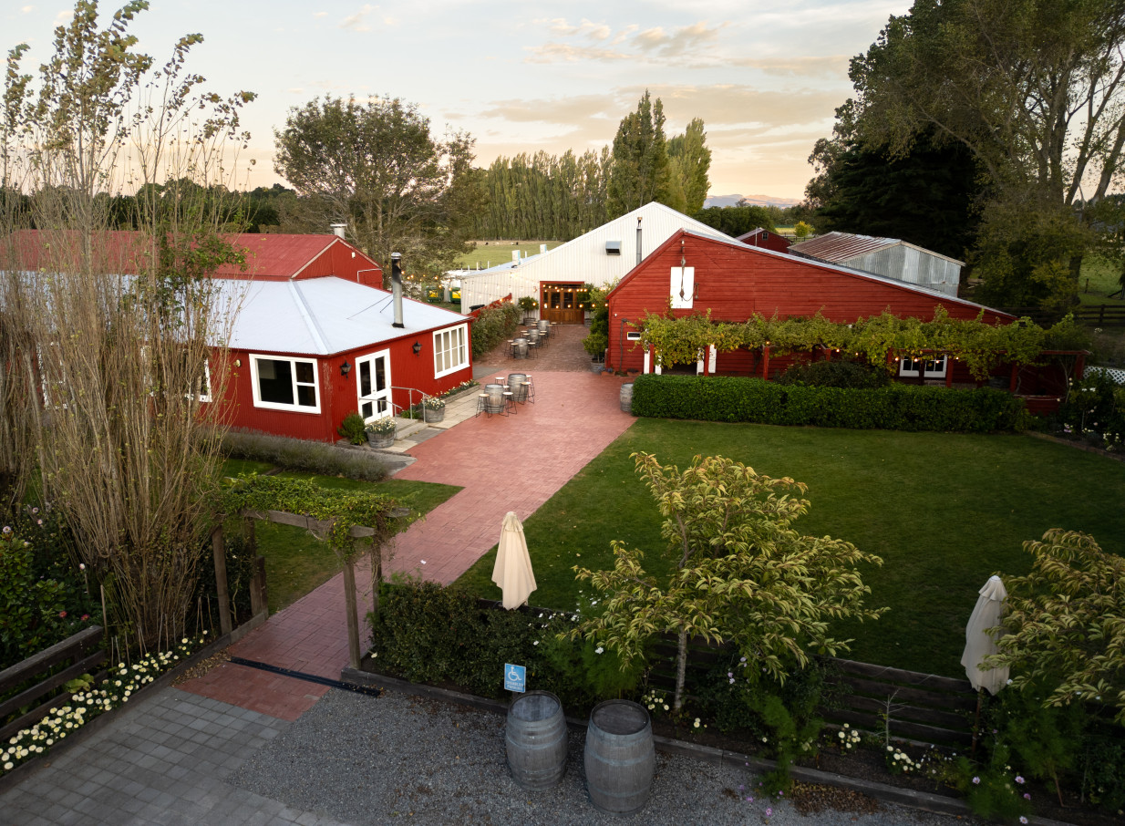 The rustic red barn buildings and paved outdoor courtyard of Larcomb Vineyard, Christchurch, offer an elegant event setting.