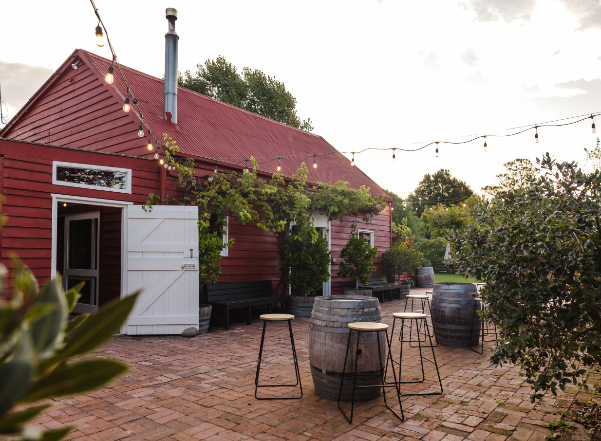 The rustic barn courtyard at Larcomb Vineyard, Christchurch, is set for an outdoor gathering under string lights.