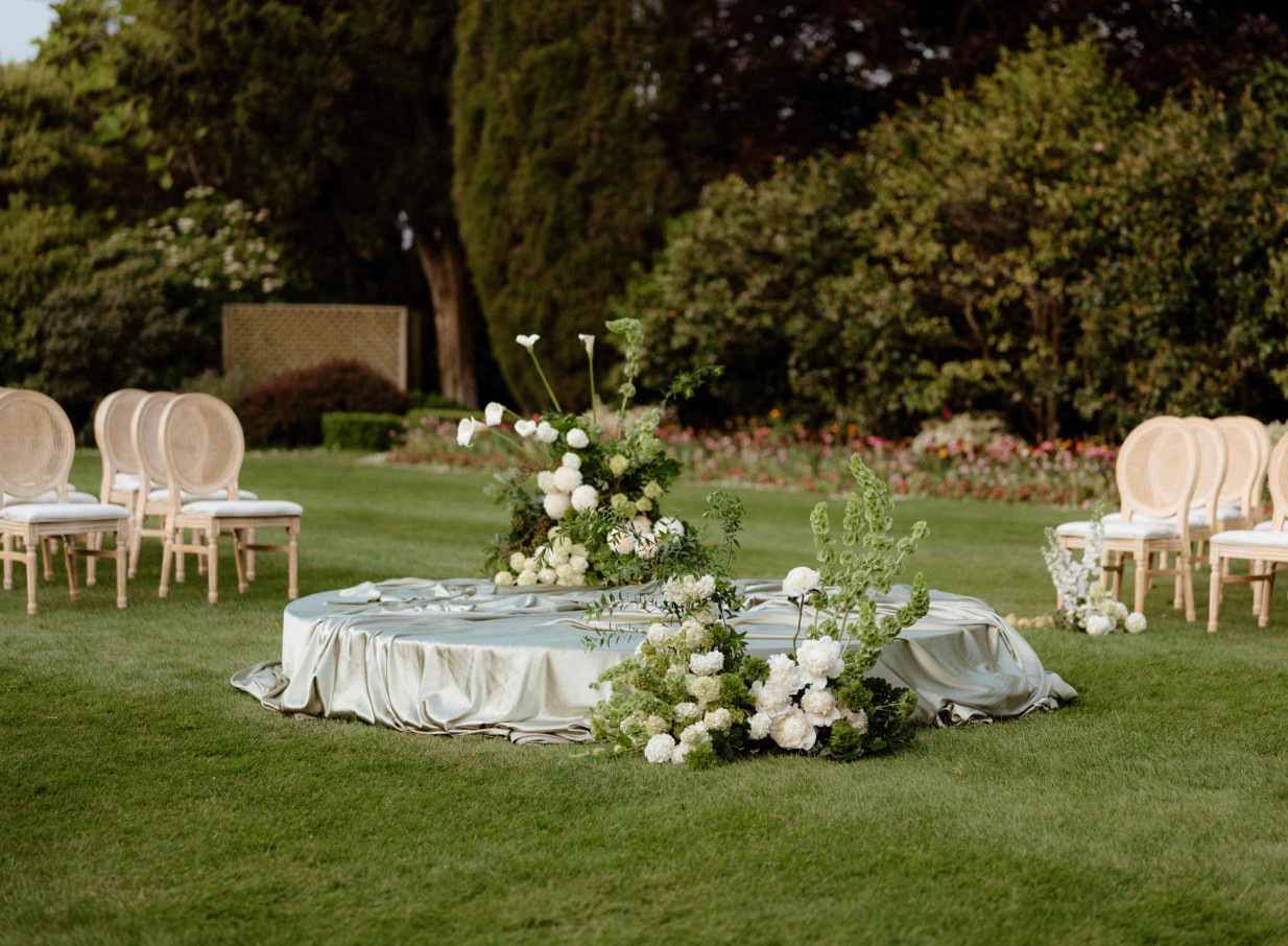 Elegant outdoor ceremony with floral arrangements on the lawn of the Old English Revival Mona Vale Homestead, Christchurch.