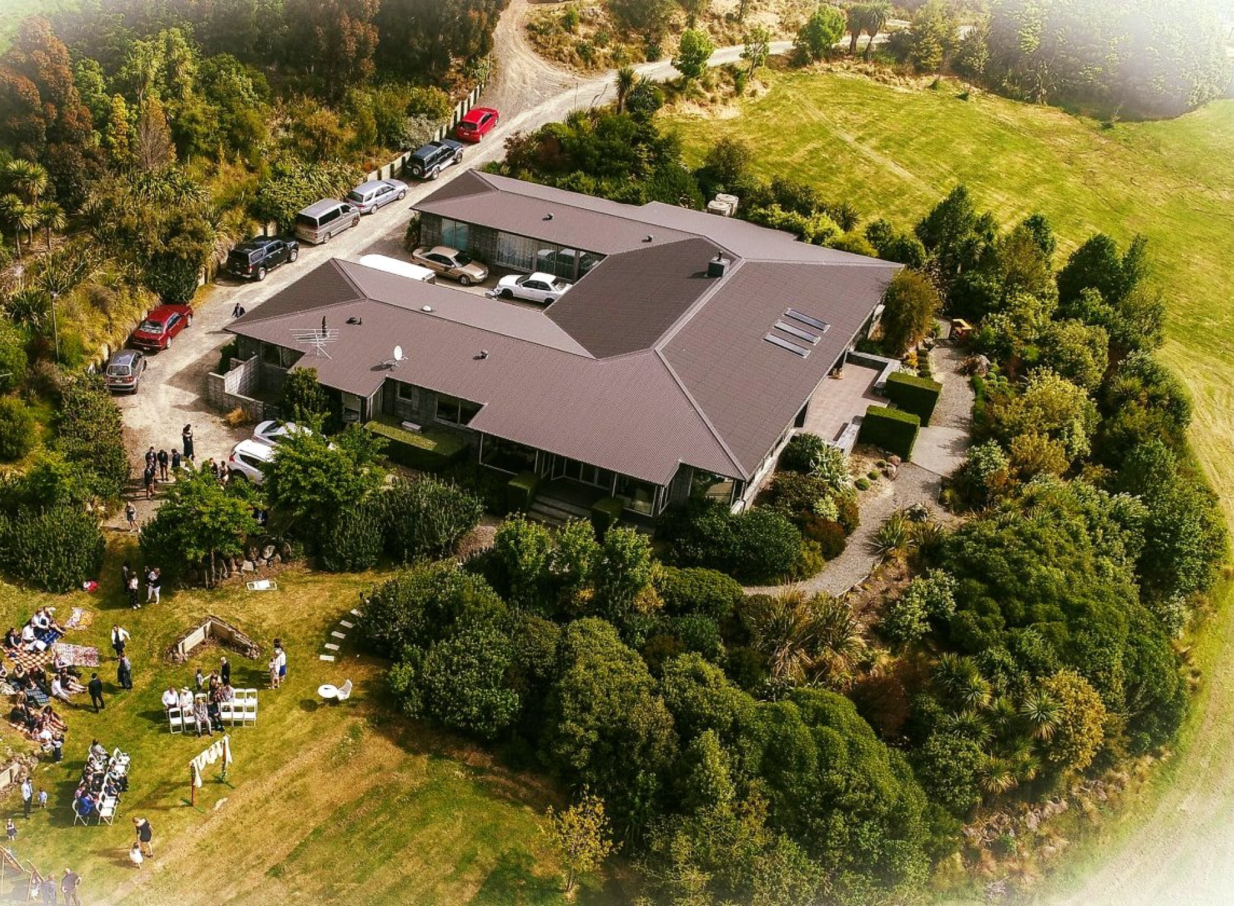 An outdoor wedding ceremony on the lawn of Waipuna Estate in Christchurch, a luxurious homestead amidst native bush.