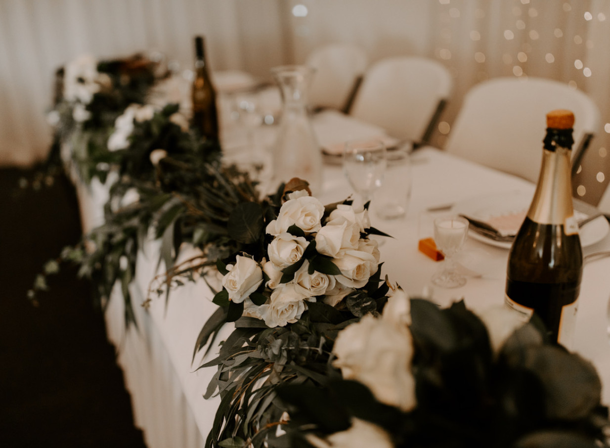 A wedding reception table with white rose and greenery decor at the elegantly rustic Omarino Estate, Christchurch.