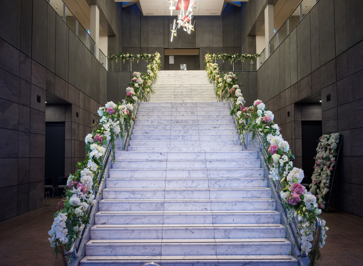 A dramatic, modern marble staircase elegantly adorned with flowers within the Christchurch Art Gallery Te Puna o Waiwhetū.