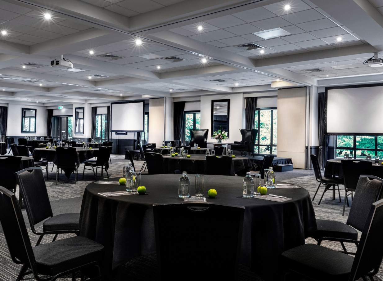 Rydges Latimer, Christchurch's modern conference space, set with round tables, screens, and abundant natural light.