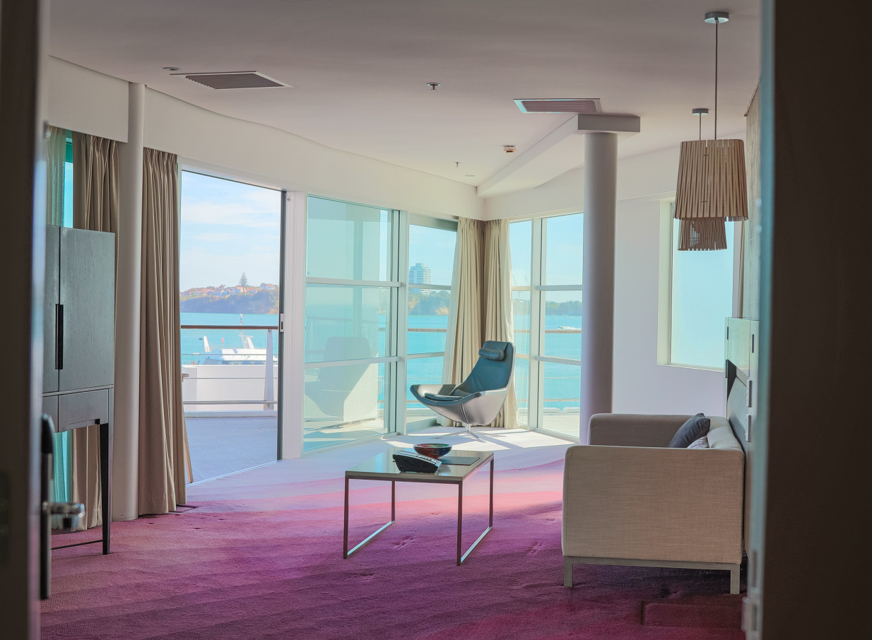 A contemporary, nautically-inspired suite at Hilton Auckland, offering panoramic harbor views from its private balcony.