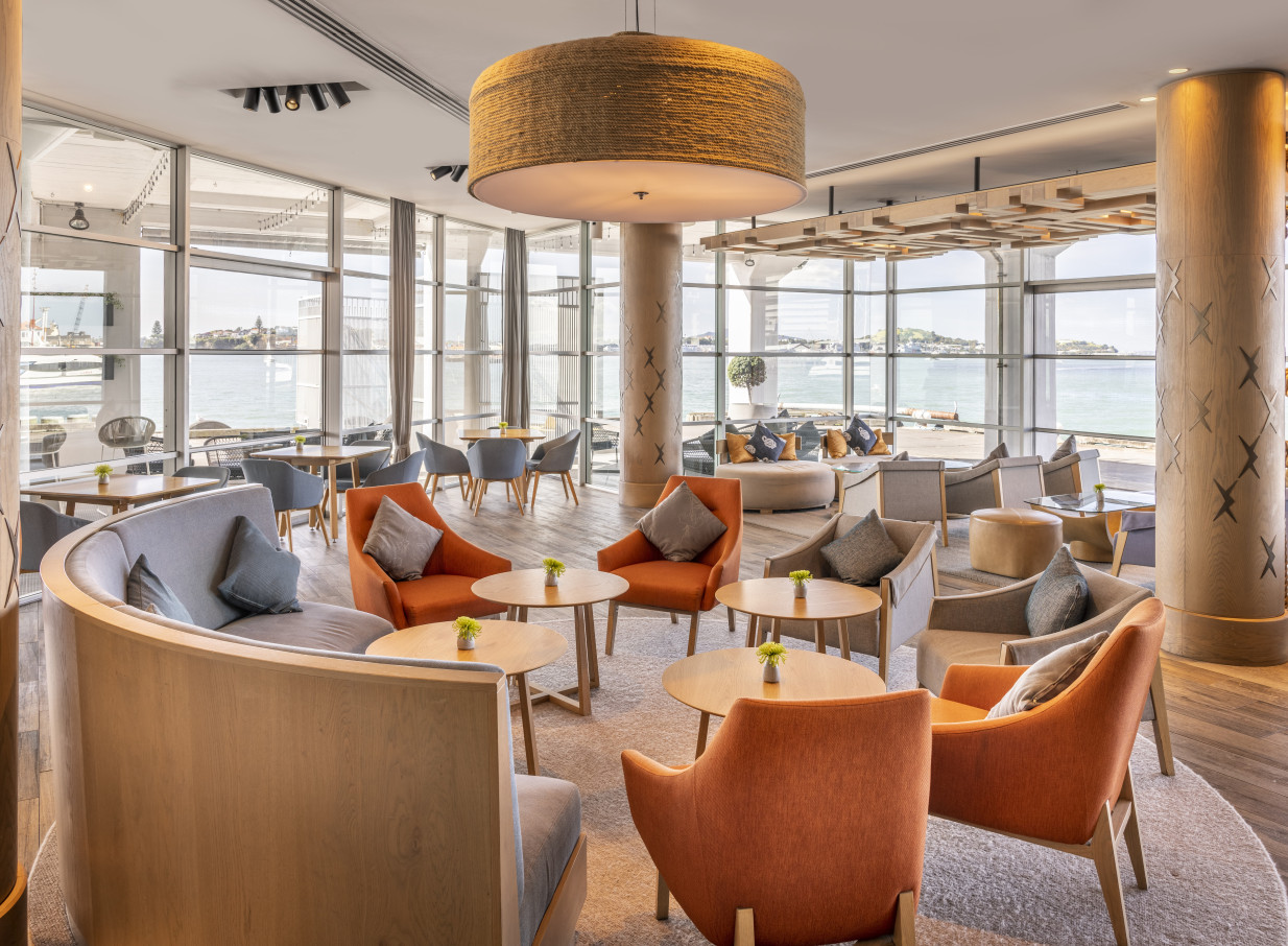 A modern, nautical-inspired lounge at Hilton Auckland offers stylish seating with panoramic harbor views.