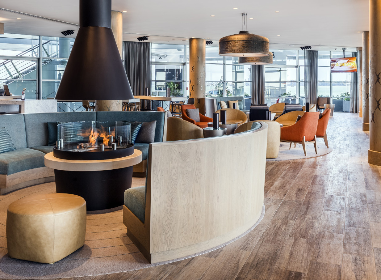 The Hilton Auckland's sleek, nautical-inspired lounge features a central circular fireplace and expansive harbor views.