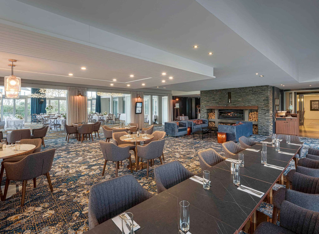 The contemporary dining and lounge area at Peppers Clearwater Resort, Christchurch, boasts a stone fireplace and patterned carpet.