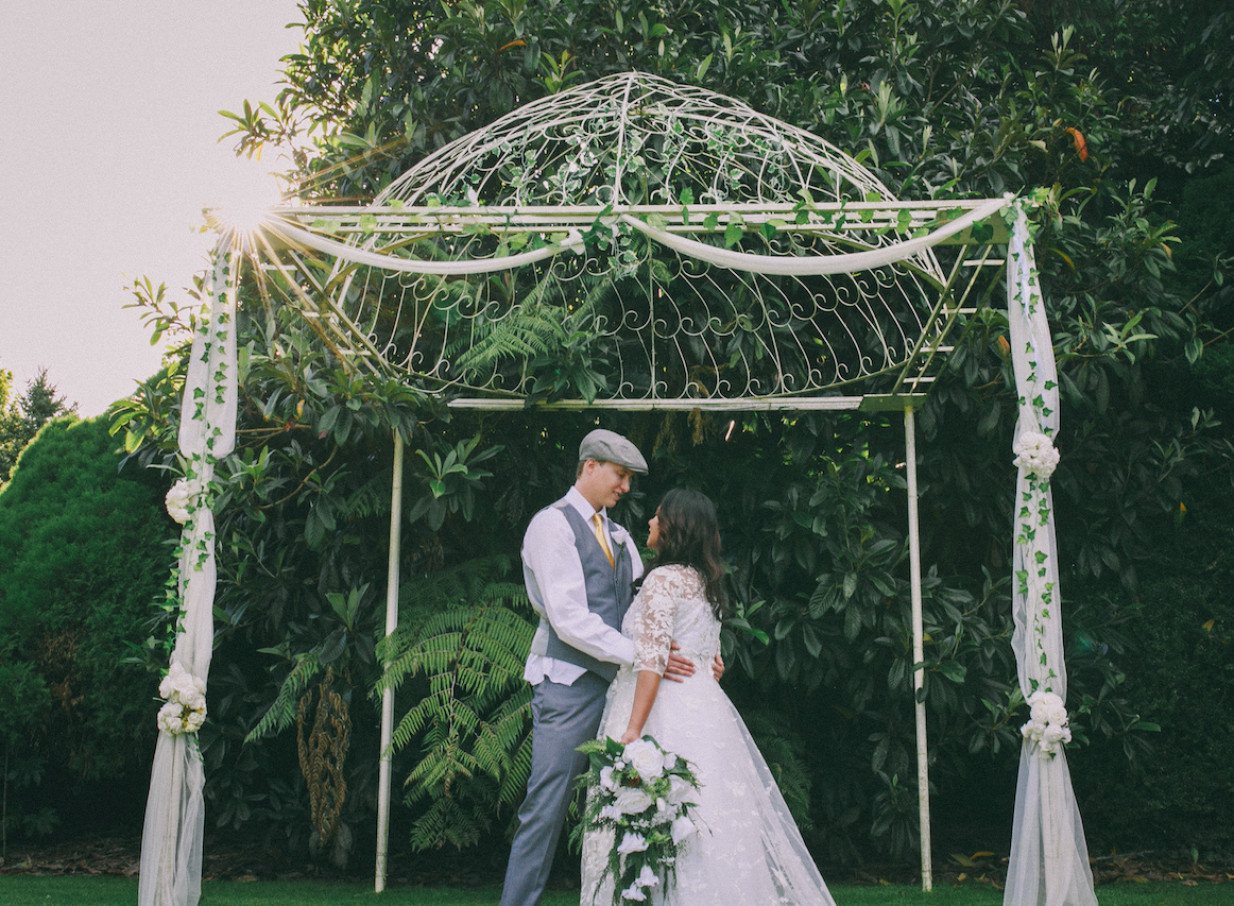 An outdoor wedding portrait of a couple beneath an elegant garden dome at Gails of Tamahere, Hamilton.