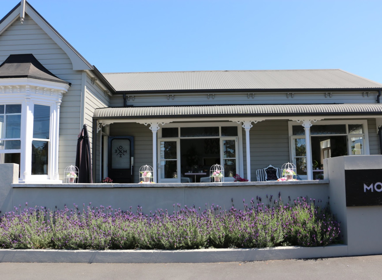 Auckland's Moxie, a beautifully restored villa, displays its inviting exterior with a classic porch and lavender.