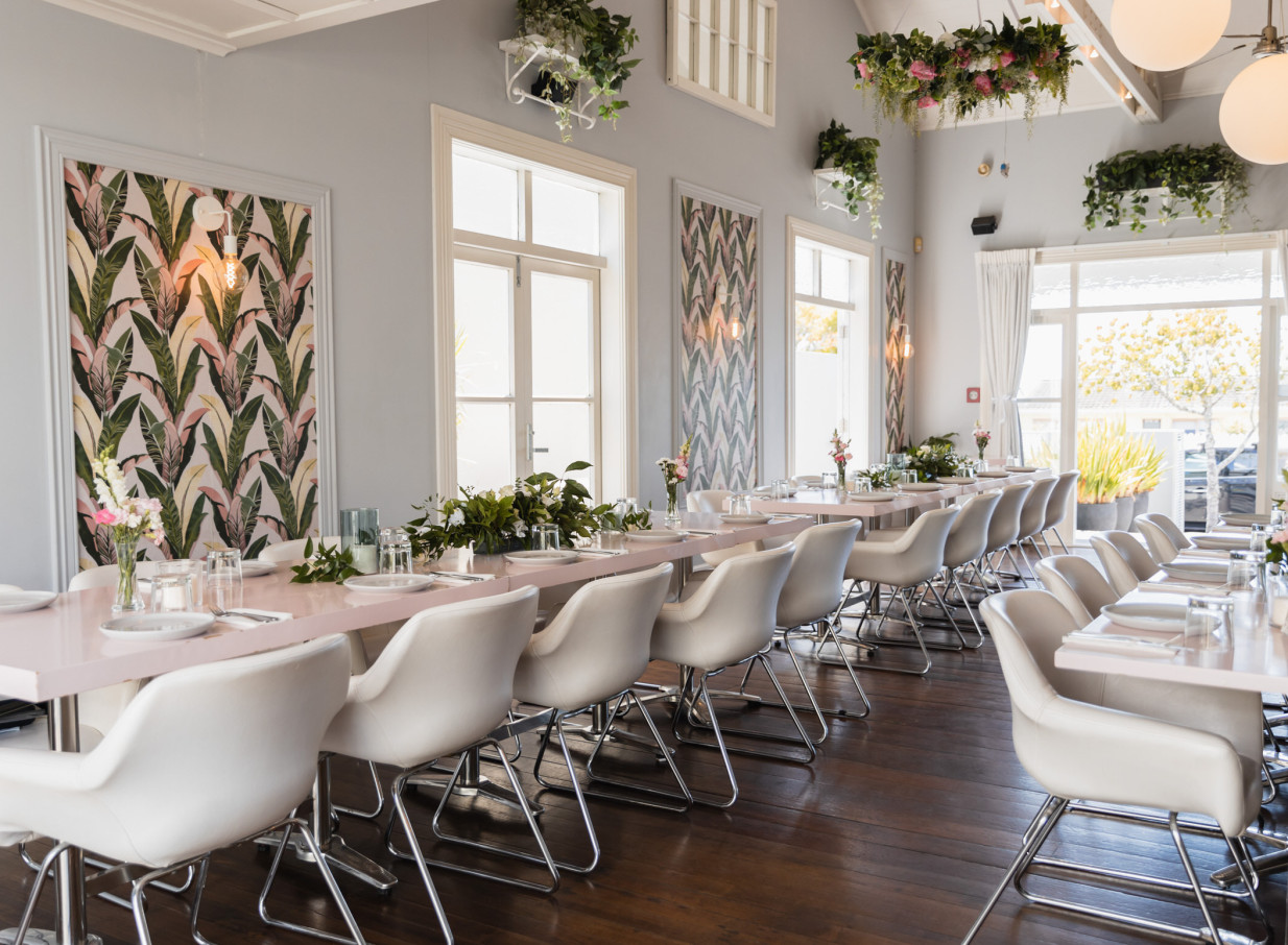 Moxie, a modern eatery set in a charming Auckland villa, features a vibrant dining room with pastel tables and lush floral accents.