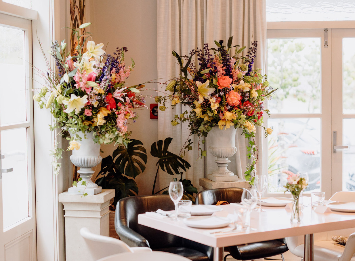 Vibrant floral arrangements adorn a private dining room at Moxie, an elegant villa restaurant in Auckland.