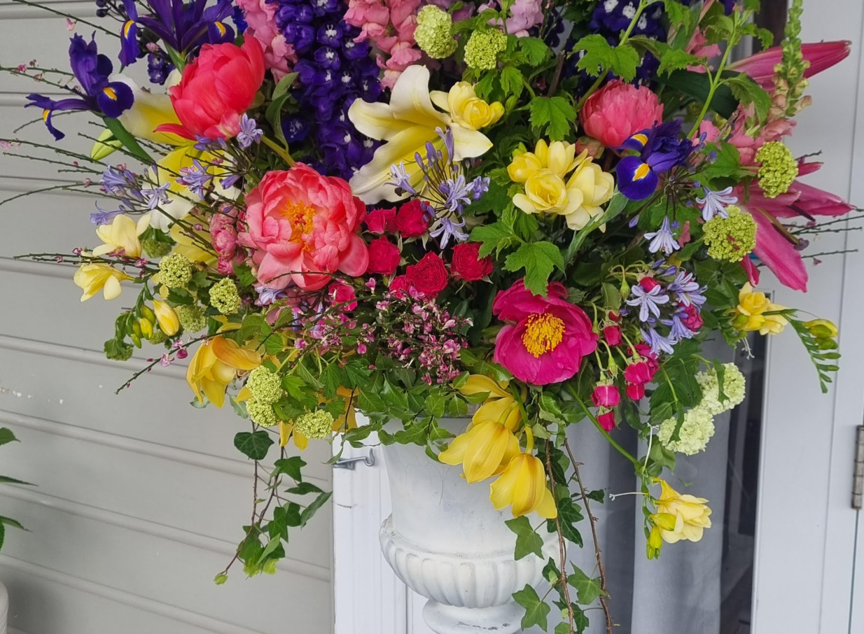A lush, colorful floral arrangement in an urn, enhancing the charming villa ambiance of Moxie in Auckland.