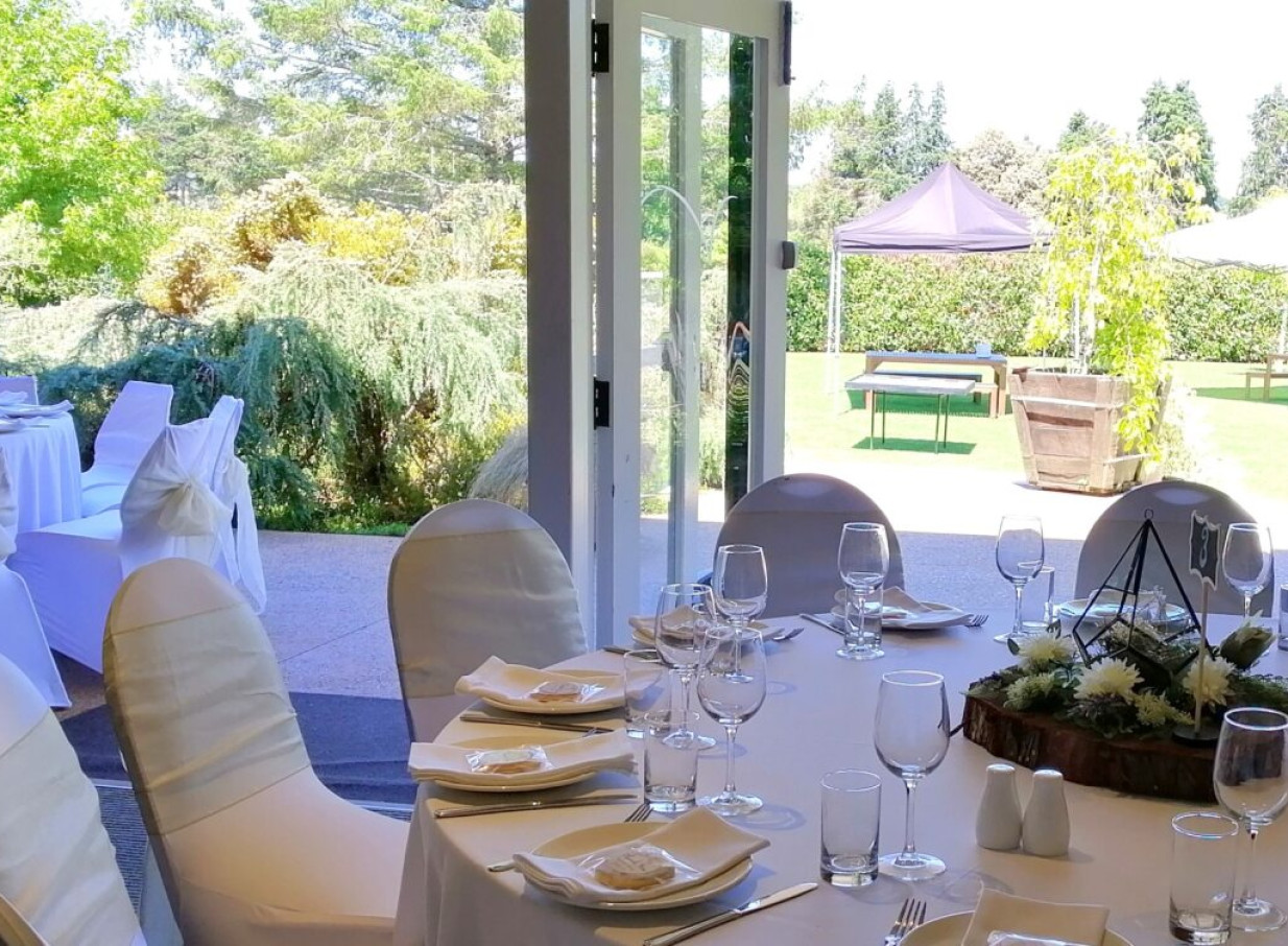 An elegant dining area at LaValla, an Auckland country venue, offering scenic views of lush, natural gardens.