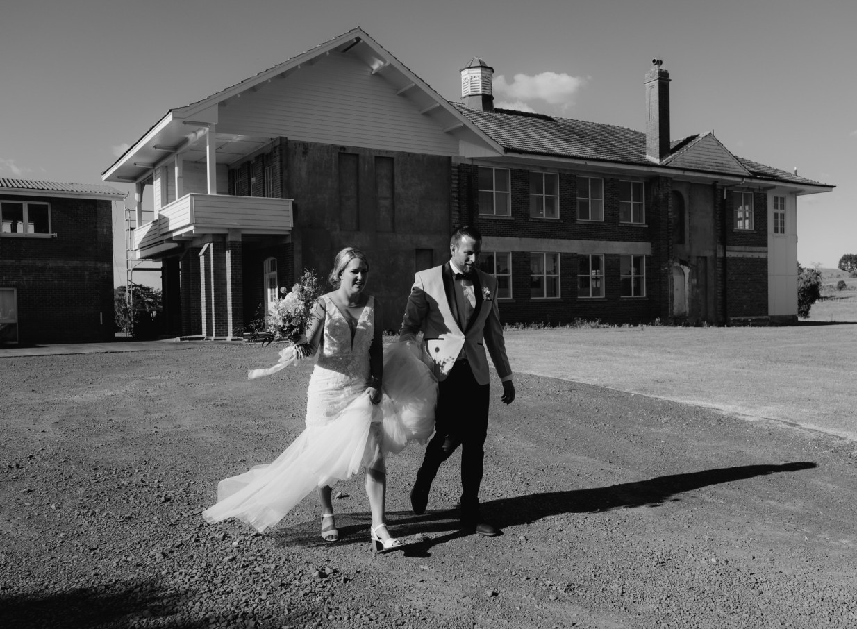 Newlyweds walk outside the historic brick lodge at LaValla Estate, a charming country venue near Auckland.