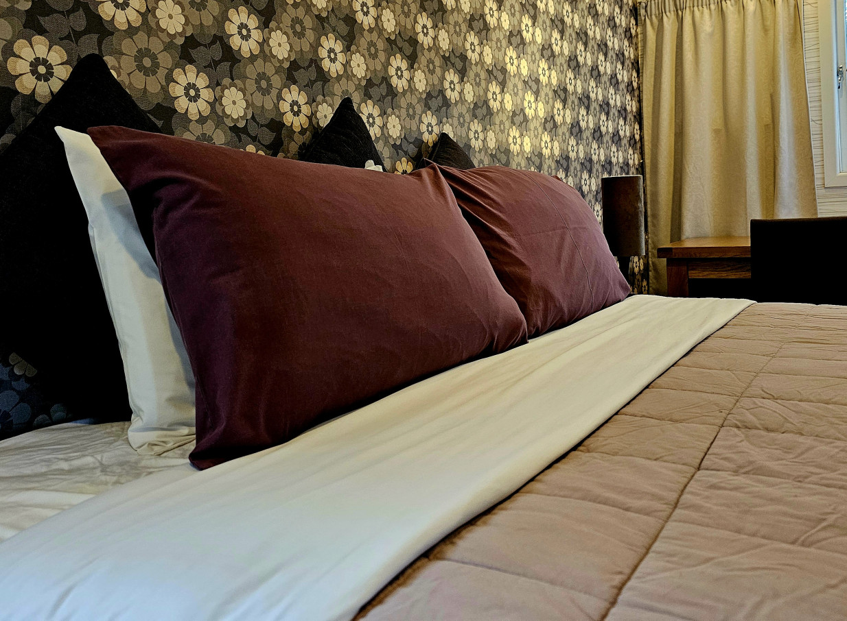 A stylish, warmly decorated bedroom featuring a floral accent wall at LaValla, an award-winning country venue in Auckland.