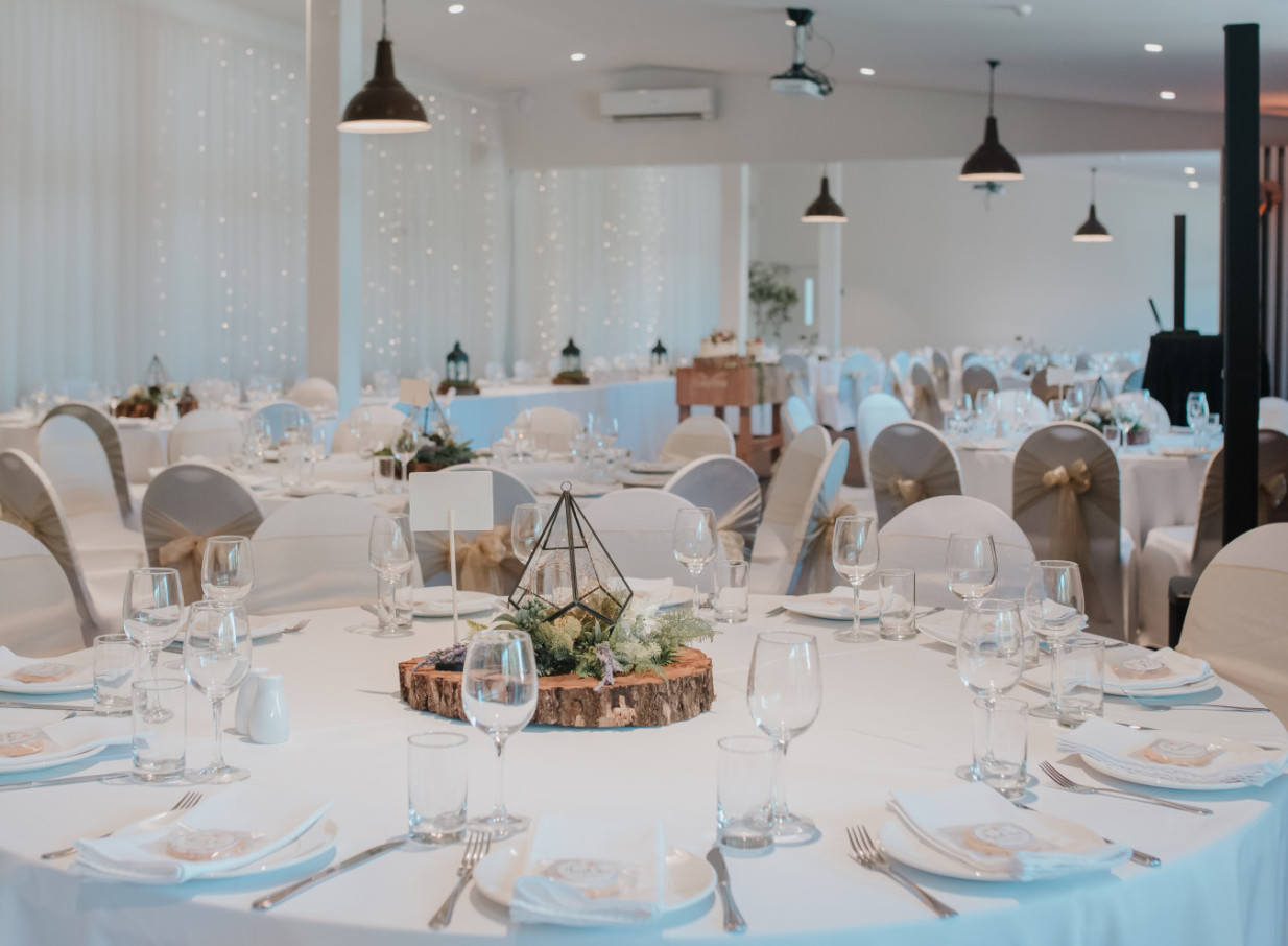 An elegant dining room at LaValla Estate in Auckland, a country venue, features white table settings and rustic-chic centerpieces.