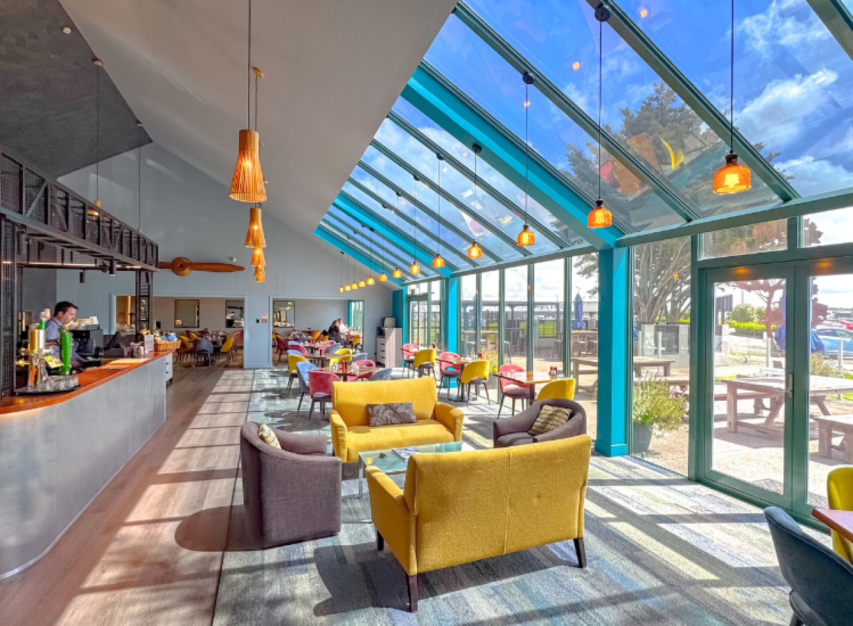This modern, bright restaurant and bar area with a glasshouse-inspired roof is located at JetPark Hamilton Hotel.