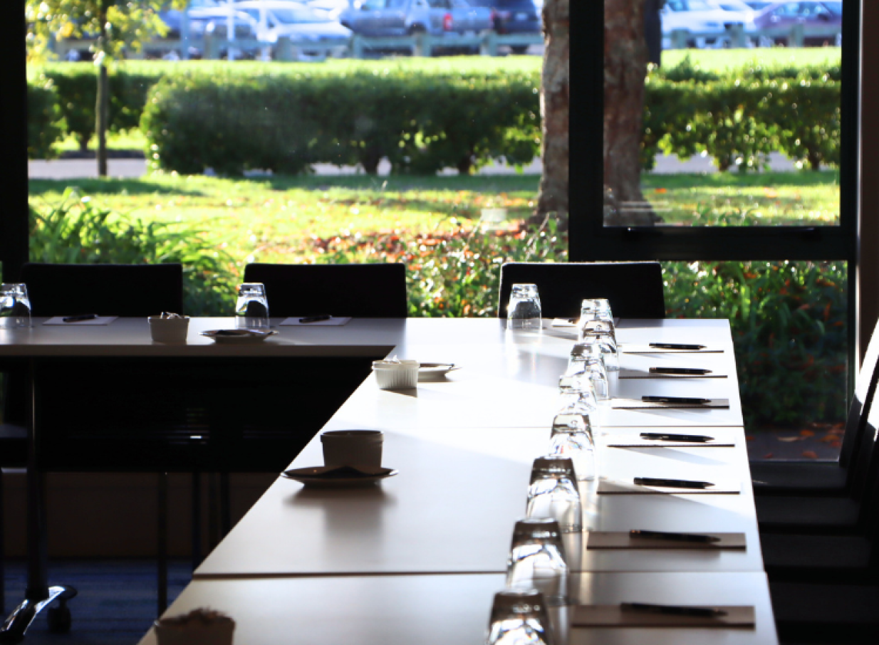 JetPark Hamilton Hotel's modern conference space, prepared for a meeting, features natural light and views of lush greenery.