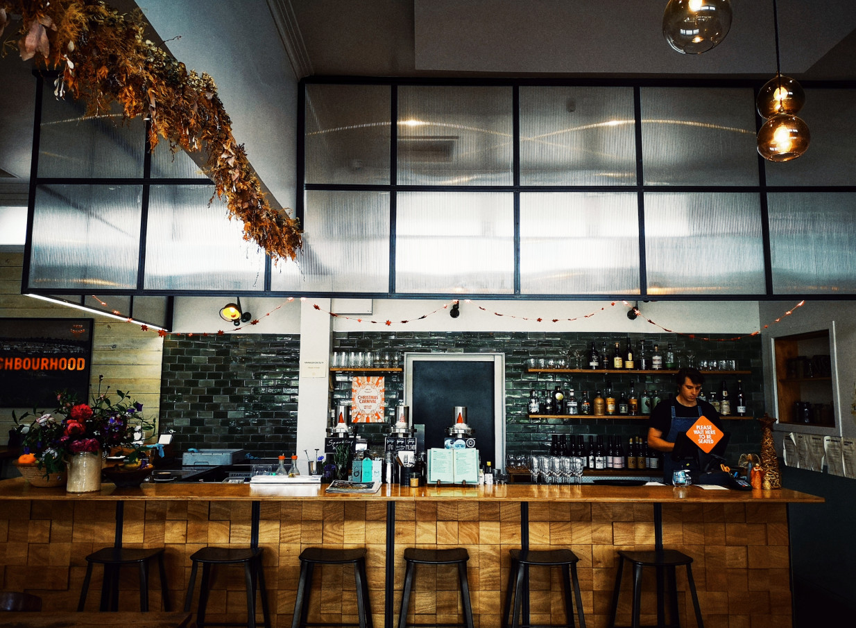 The inviting bar at Hayes Common, Hamilton, combines a modern, relaxed style with mid-century elements like green tiles and a timber counter.