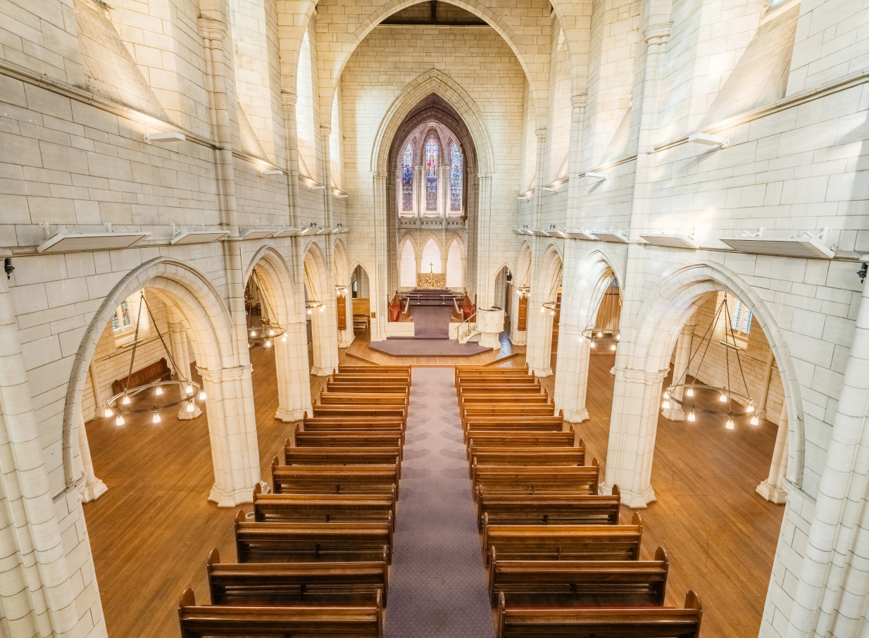 The majestic Gothic Revival interior of St Matthew-in-the-City in Auckland, showing its nave, pews, and altar.