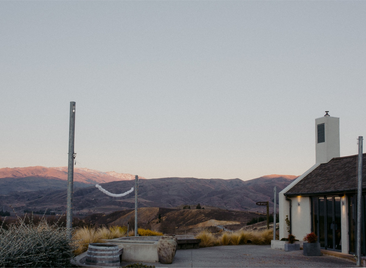 The contemporary Mt Difficulty Cellar Door in Central Otago, with an outdoor area overlooking a rugged mountain landscape.