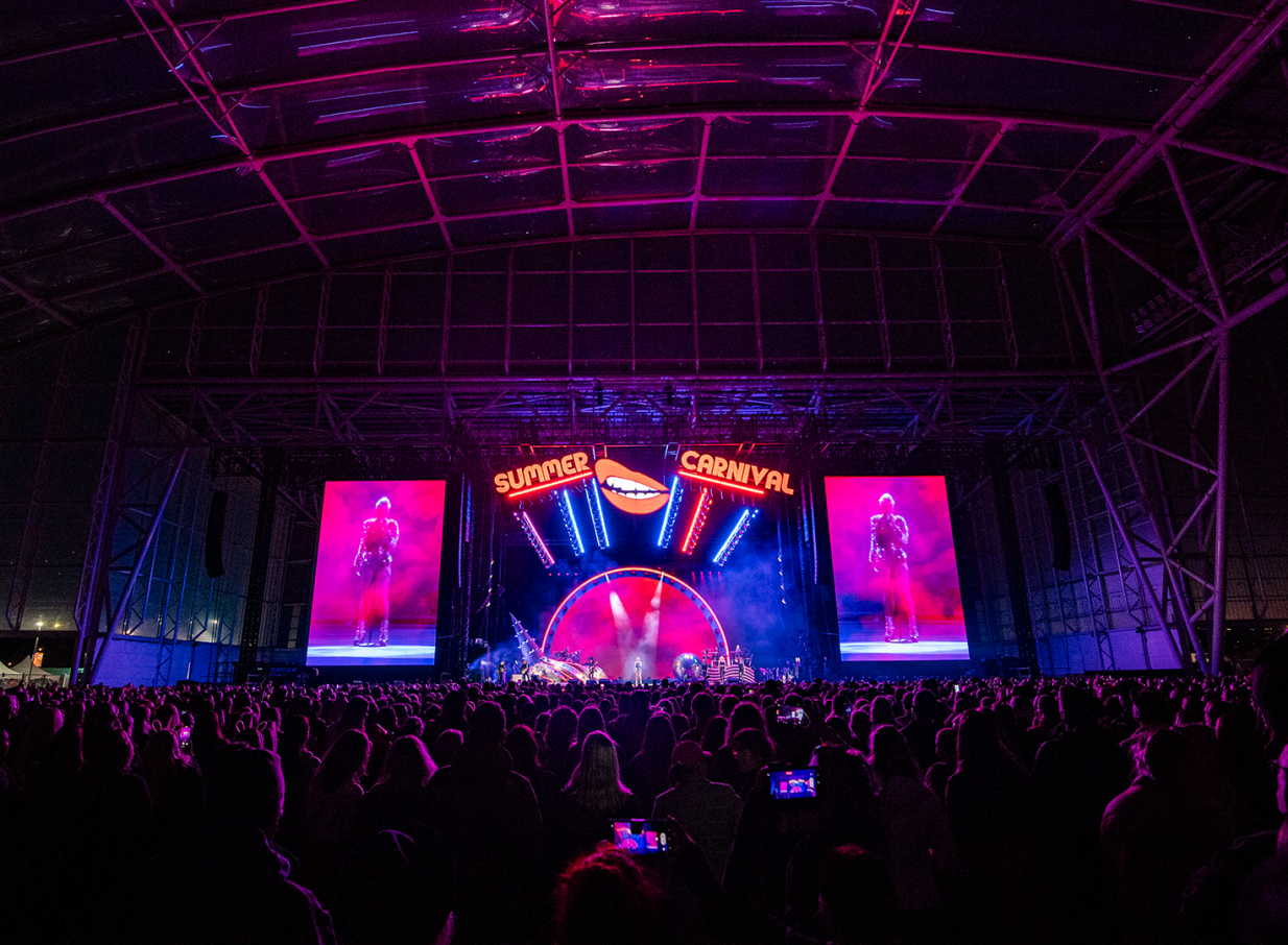 A vibrant concert fills Dunedin's modern Forsyth Barr Stadium, also known as 'The Glasshouse,' under its transparent roof.