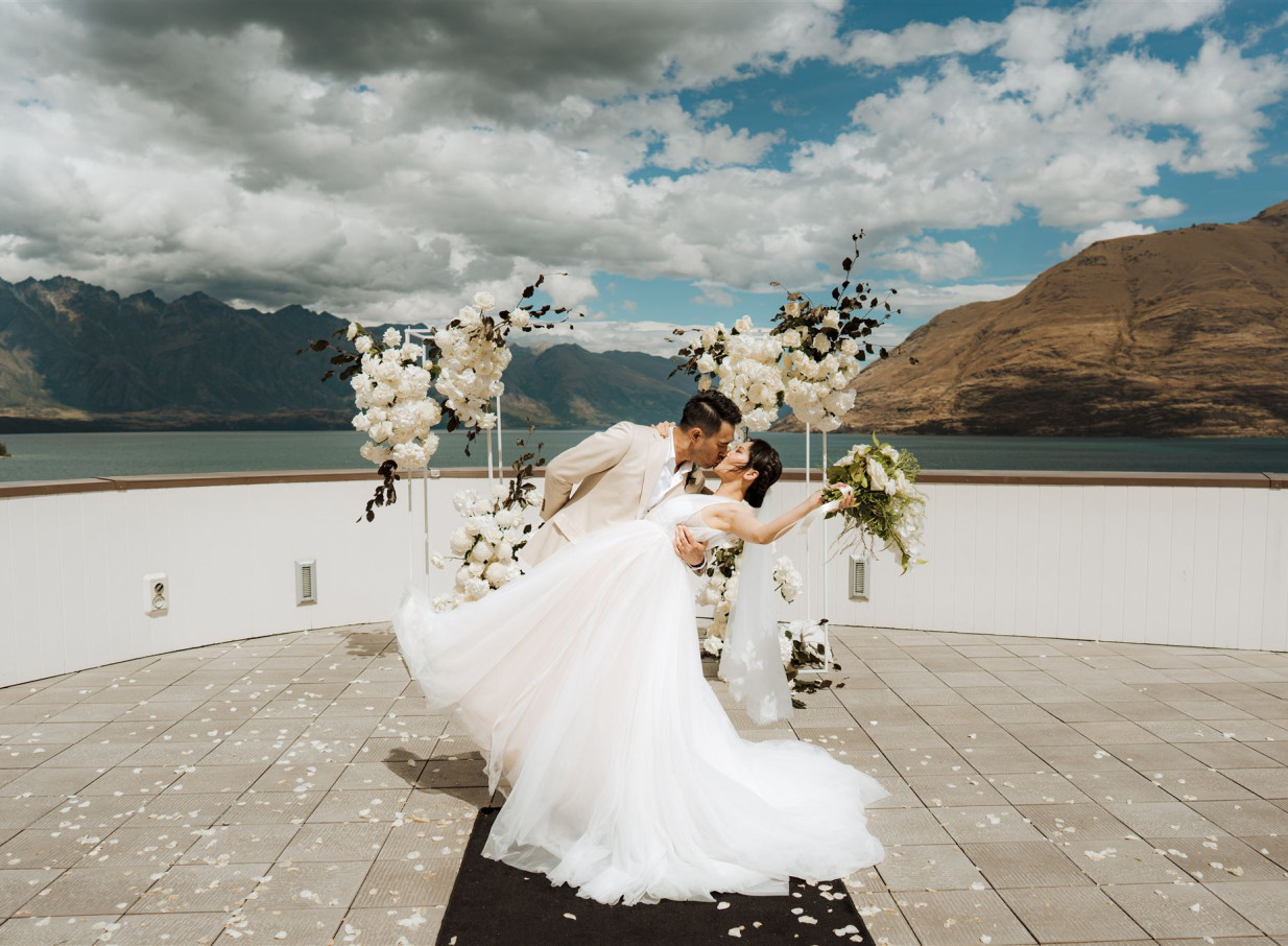 A couple shares a kiss during an outdoor wedding ceremony on the modern alpine lodge rooftop terrace of Rendezvous Heritage Hotel Queenstown.