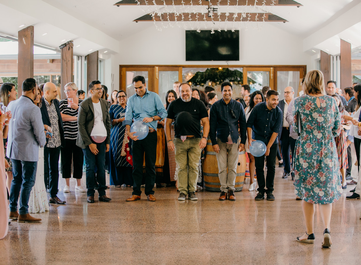 Guests enjoy a balloon game in the bright, modern reception space with high ceilings and large windows at Markovina Vineyard Estate, Auckland.