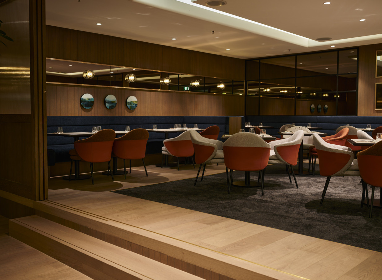 A chic, modern dining room with warm wood paneling and stylish seating at Grand Millennium Auckland.