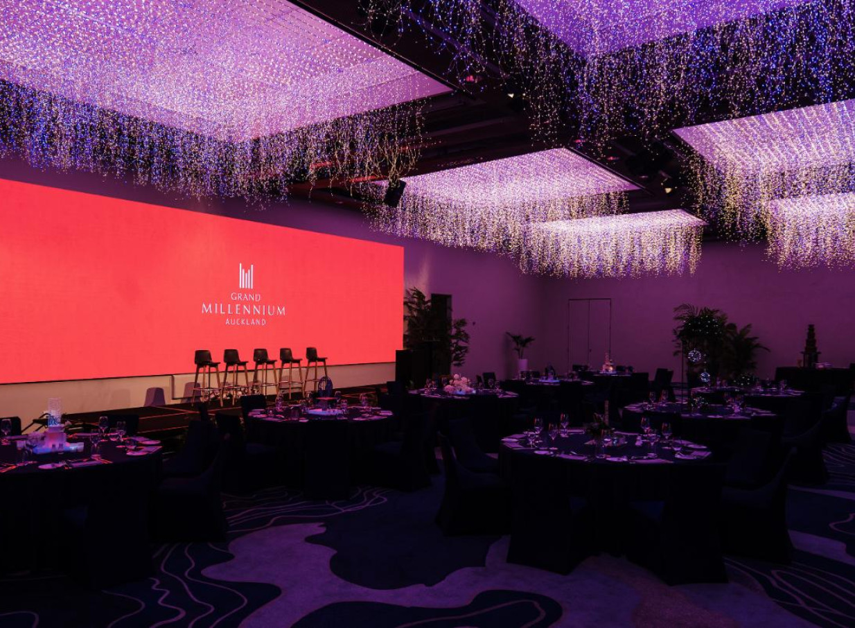 Grand Millennium Auckland's modern ballroom features its "Sky Garden" LED lighting, illuminating an elegant event setup.