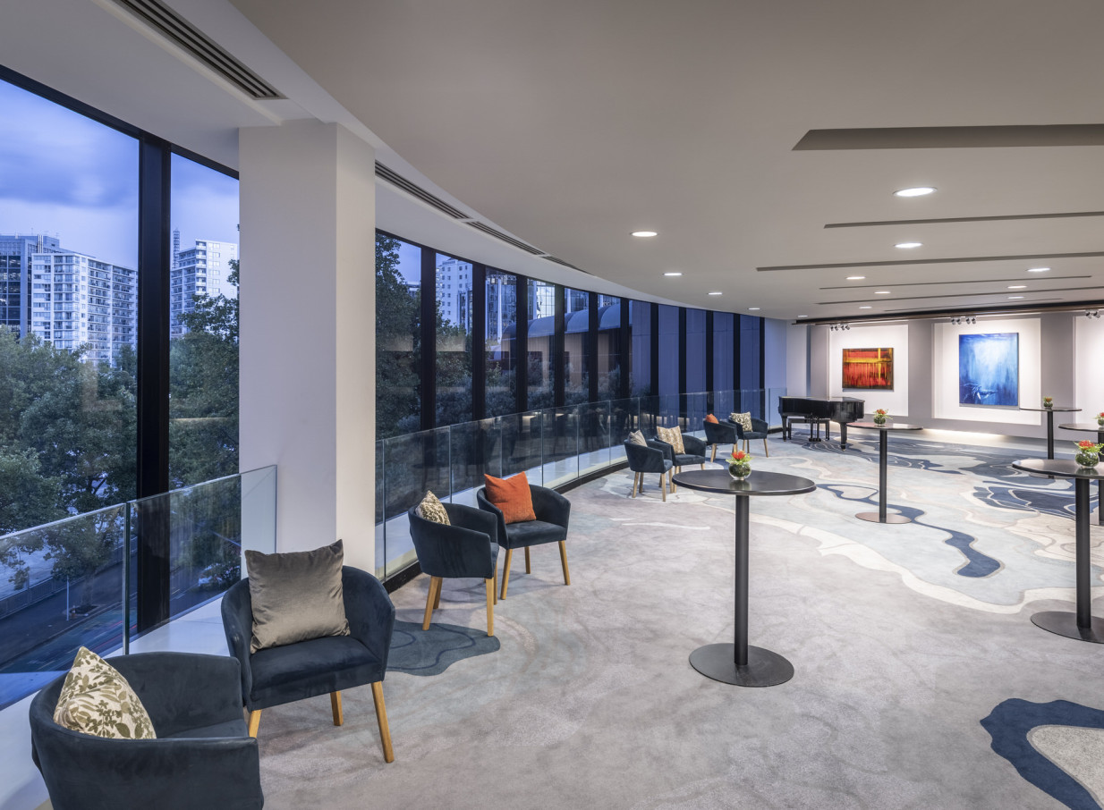 The Grand Millennium Auckland's modern event lounge features elegant decor, floor-to-ceiling windows, and city views.