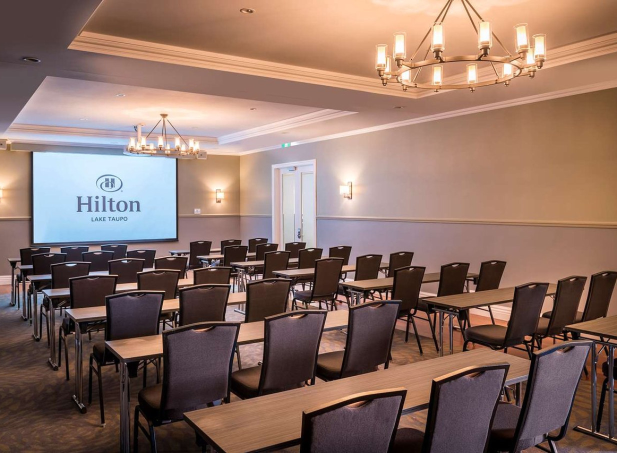 This elegant meeting room at the Hilton Lake Taupo blends Victorian charm with modern design, featuring a large projection screen.