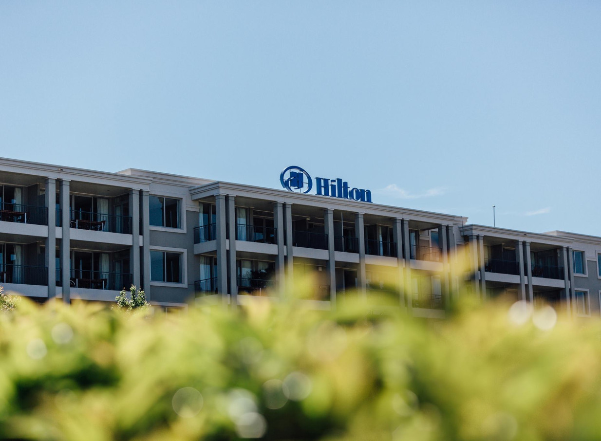The modern resort-style exterior of the Hilton Lake Taupo hotel in Taupo, featuring numerous guest balconies.