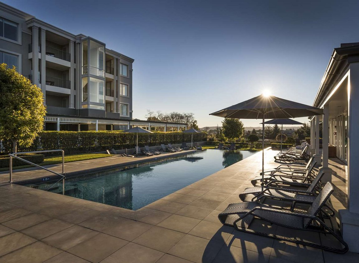 An outdoor pool area with lounge chairs at Hilton Lake Taupo, a hotel blending Victorian charm and modern style in Taupo.