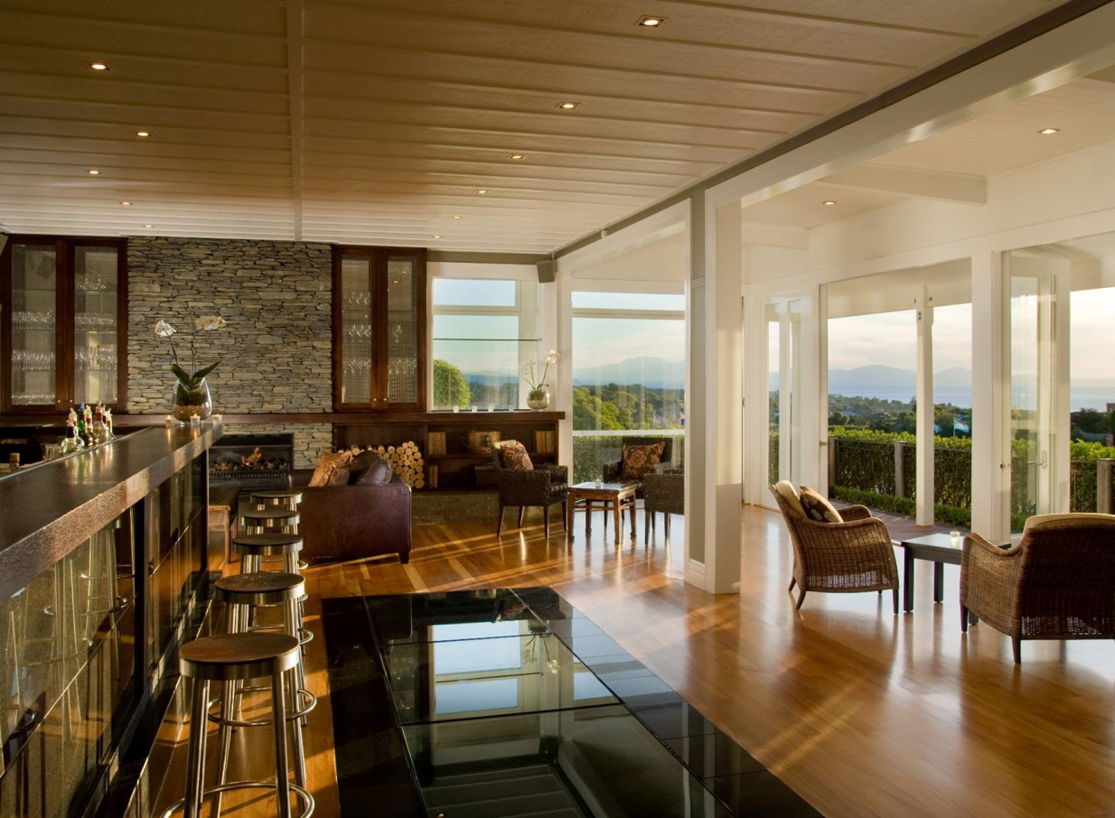 The modern bar and lounge at Hilton Lake Taupo, featuring natural stone, timber, and a fireplace, offers scenic views.