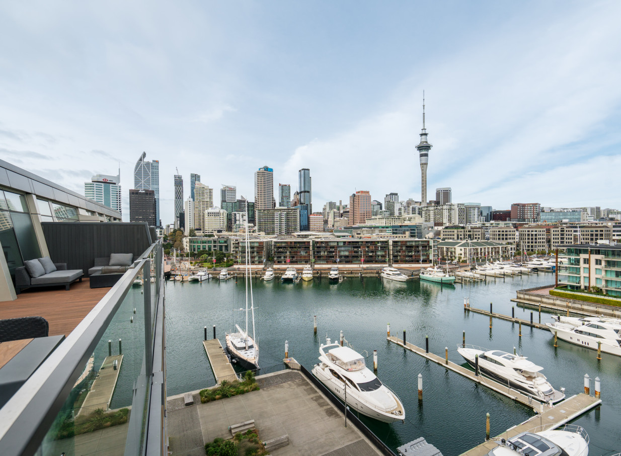 Park Hyatt Auckland's modern waterfront terrace offers lounge seating and panoramic views of the marina and Auckland city skyline.
