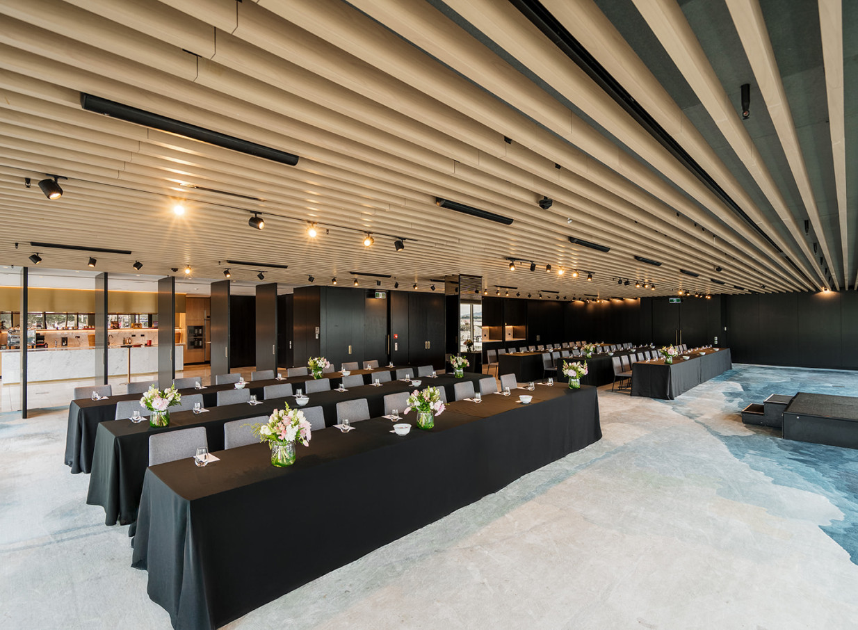 Auckland's Park Hyatt offers a modern event space with a distinct timber-slatted ceiling, set for a conference.